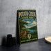 A vintage-style metal sign for Potato Creek State Park in Indiana, featuring a scenic illustration of a path leading to a lake surrounded by trees.