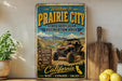 a vintage-style metal sign that reads "Welcome to Prairie City State Vehicular Recreation Area" with an illustration of an off-road vehicle in the background.
