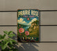 A vintage-style metal sign for Prairie Rose State Park in Iowa, featuring a scenic landscape with a river, mountains, and pink flowers.