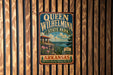 A vintage-style metal sign for Queen Wilhelmina State Park in Arkansas, featuring a scenic landscape with a cabin and mountains in the background.