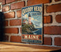 A vintage metal sign for Quoddy Head State Park in Maine, featuring a lighthouse and a coastal scene.