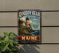 A vintage-style metal sign for Quoddy Head State Park in Maine, featuring a lighthouse and coastal scenery.