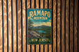 A vintage metal sign for Ramapo Mountain State Forest in New Jersey, featuring a scenic landscape with mountains, trees, and a lake.