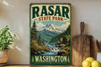 A vintage-style sign for "RASAR STATE PARK" in Washington, featuring a scenic mountain landscape with a waterfall.