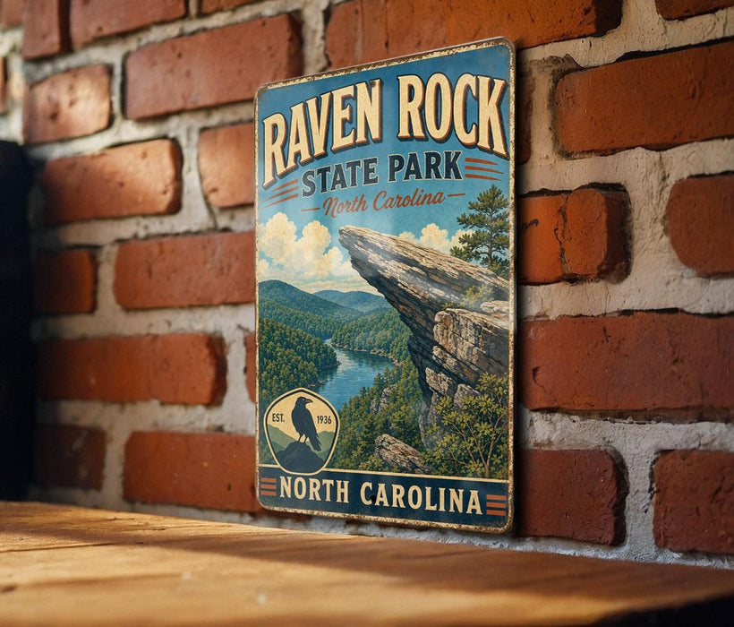 A vintage-style metal sign for Raven Rock State Park in North Carolina, featuring a scenic mountain landscape with a river and a cliff.