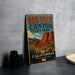 A vintage-style metal sign for Red Rock Canyon State Park in California, featuring a desert landscape with mountains and a bear.