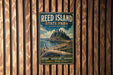 A vintage-style metal sign for Reed Island State Park in Washington, featuring a scenic landscape with a mountain, trees, and a body of water.