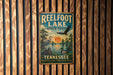 A vintage metal sign for Reelfoot Lake State Park in Tennessee, featuring an illustration of a bird, a duck, and a sunset over the lake.