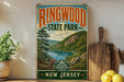 A vintage-style sign for Ringwood State Park, featuring a scenic landscape with a lake and mountains, is displayed on a shelf next to a wooden cutting board and some potted plants.