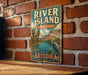 A vintage-style sign for River Island State Park in Arizona, featuring a scenic landscape with palm trees, mountains, and a bird.