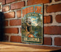 A vintage-style metal sign for Robbers Cave State Park in Oklahoma, featuring a scenic image of the cave and surrounding landscape.