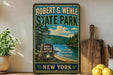 A vintage-style metal sign for Robert G. Wehle State Park, featuring a scenic landscape with pine trees, a lake, and mountains.