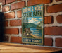 A vintage-style metal sign for Robert G. Wehle State Park, featuring a scenic landscape with pine trees, a lake, and mountains.