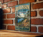 A vintage metal sign for Robinson State Park in Massachusetts, featuring a scenic landscape with pine trees, a lake, and mountains.