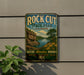 A vintage-style metal sign for Rock Cut State Park in Illinois, featuring a scenic landscape with a river, cliffs, and flowers.