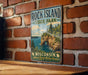 A vintage-style sign for Rock Island State Park in Wisconsin, featuring a scenic landscape with cliffs, water, and pine trees.
