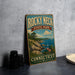 A vintage-style sign for Rocky Neck State Park in Connecticut, featuring a scenic landscape with a rocky coastline, a lake, and a sailboat.