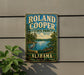 A vintage metal sign for Roland Cooper State Park in Alabama, featuring a scenic illustration of a lake, trees, and a bird.