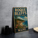 A vintage-style metal sign for Roque Bluffs State Park in Maine, featuring a scenic landscape with a beach, mountains, and pine trees.
