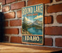 A vintage metal sign for Round Lake State Park in Idaho, featuring a scenic illustration of the lake surrounded by mountains and pine trees.