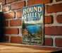 A vintage metal sign for the Round Valley Recreation Area in New Jersey, featuring a scenic image of a lake and mountains.