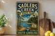 A vintage-style sign for Sadlers Creek State Park in South Carolina, featuring a scenic landscape with a lake and forest.