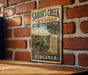 A vintage metal sign for Sailor's Creek Battlefield Historical State Park in Virginia, featuring a cannon and a monument, mounted on a brick wall.