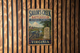 A vintage metal sign for Sailor's Creek Battlefield Historical State Park in Virginia, featuring a cannon and a gravestone, mounted on a wooden wall.