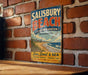 A vintage metal sign for Salisbury Beach, Massachusetts, featuring a beach scene and the text "Sun, Sand & Sea Natural Beauty - Family Fun Make Memories - Last A Lifetime".