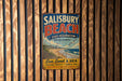 A vintage metal sign for Salisbury Beach, Massachusetts, featuring a beach scene and the text "Sun, Sand & Sea Natural Beauty - Family Fun Make Memories that Last a Lifetime".