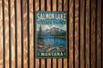 A metal sign for Salmon Lake State Park in Montana, featuring a scenic landscape with mountains, a lake, and a pine tree.