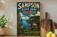 A vintage-style sign for the state park of New York, featuring a scenic landscape with a lake and mountains.