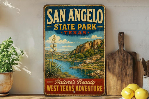 A vintage-style metal sign for San Angelo State Park in Texas, featuring a scenic landscape with a river, mountains, and desert vegetation.
