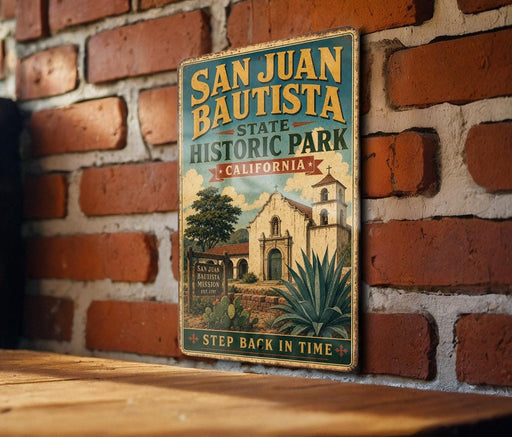 A vintage-style metal sign for San Juan Bautista State Historic Park in California, featuring an illustration of a historic building and a palm tree.