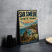 A vintage metal sign for San Simeon State Park in California, featuring a scenic image of a seal on the beach and the ocean.