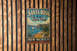 A vintage metal sign for Santa Rosa Lake State Park in New Mexico, featuring a scenic illustration of the lake and mountains.