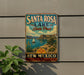 A vintage-style metal sign for Santa Rosa Lake State Park in New Mexico, featuring a scenic landscape with a sailboat and mountains in the background.