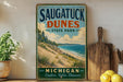 A vintage-style sign for Saugatuck Dunes State Park in Michigan, featuring a scenic beach landscape with sand dunes and a body of water.