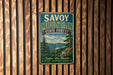 A vintage metal sign for Savoy Mountain State Forest in Massachusetts, featuring a scenic landscape with pine trees, a lake, and mountains.