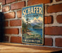 A vintage-style metal sign for Schafer State Park in Washington, featuring a scenic mountain landscape and a pine tree.