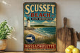 A vintage-style sign for "Scussey Beach State Reserve" in Massachusetts, featuring a lighthouse and beach scene.