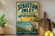 A vintage-style sign for Sebastian Inlet State Park in Florida, featuring a pelican and a beach scene with a lighthouse.