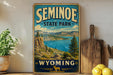 A vintage-style sign for Seminoe State Park in Wyoming, featuring a scenic landscape with mountains, a lake, and pine trees.
