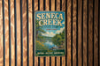 A vintage metal sign for Seneca Creek State Park in Maryland, featuring a scenic illustration of the park's natural surroundings.