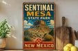 A vintage-style metal sign for Sentinal Mesa State Park in New Mexico, featuring a desert landscape with a prominent rock formation.