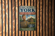 A metal sign with text and an illustration of a man in a military uniform, mounted on a wooden wall.