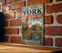 A vintage metal sign featuring a portrait of a soldier and the text "SGT. ALVIN C. YORK STATE HISTORIC PARK TENNESSEE" is displayed on a brick wall.
