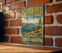 A vintage metal sign for Shadehill State Recreation Area in South Dakota, featuring a scenic landscape with a lake and mountains.