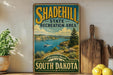 A vintage-style metal sign for the Shadehill State Recreation Area in South Dakota, featuring a scenic landscape with a lake and mountains.
