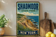 A vintage-style metal sign for Shadmoor State Park in New York, featuring a scenic coastal landscape with cliffs and the ocean.